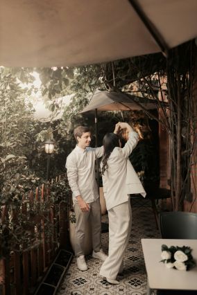 Couple dancing after wedding in privacy of a balconey, both wearing white