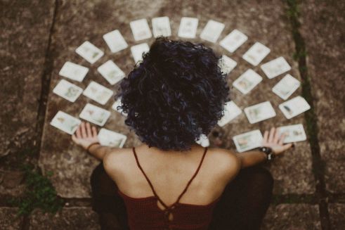 Curly hair brunett sitting and spreading tarot cards