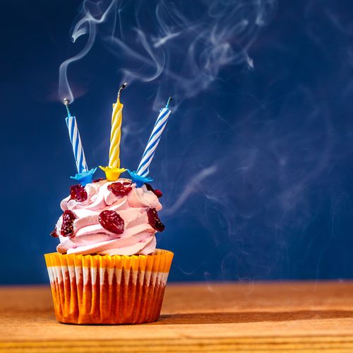 A cupcake with three blown-out candles on top of it.