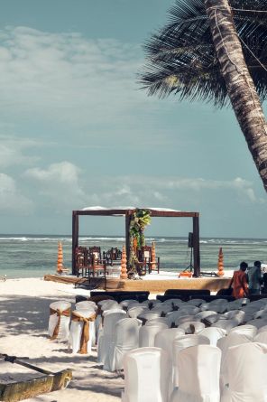 Beach destination wedding set up. Seats on the sand with a palmtree in the background.