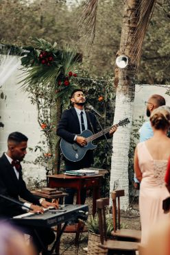 Band performing at a wedding reception playing guitar and singing, somewhere tropical with palmtrees