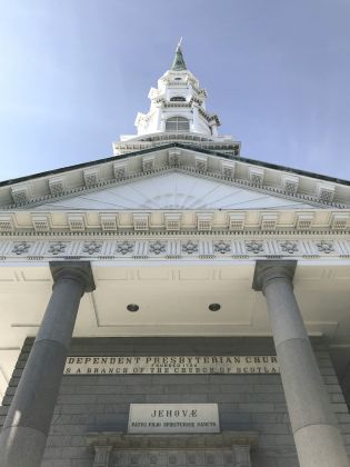 Looking up at a church from the front. Ornatitly decorated with three story spire