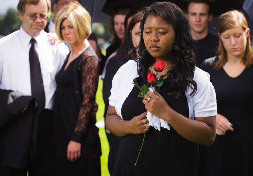 African-American minister of the Universal Life Church holding rose and crying at funeral